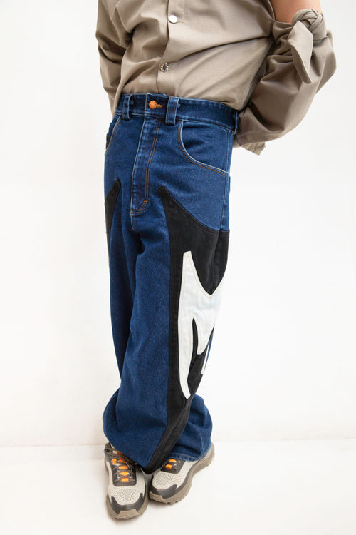MANCANDY Rider M Jeans in stone-washed blue denim featuring contrasting black M-shaped side panels and a relaxed baggy silhouette.